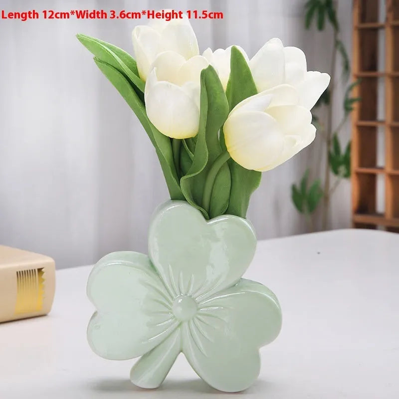 Square white porcelain clover ceramic vase on a desk, shown in light green colour.