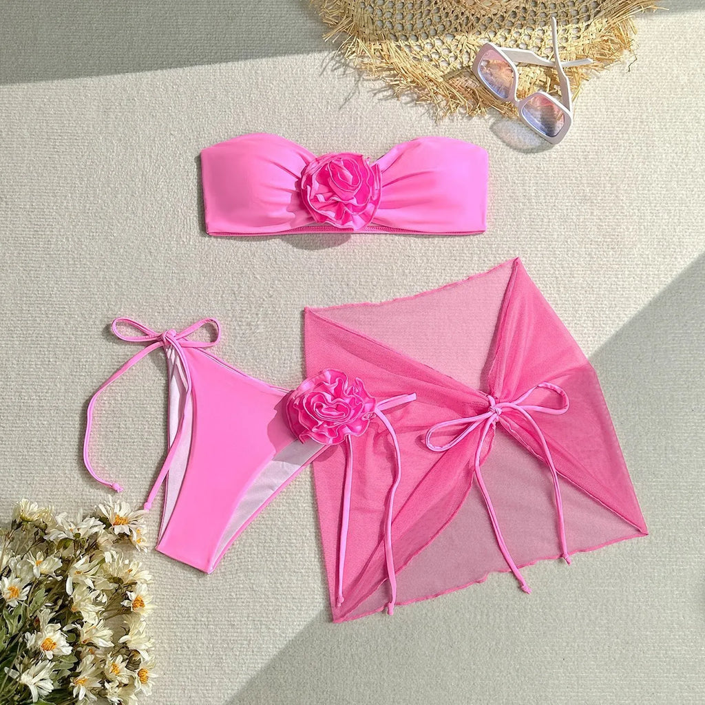 Women's pink swimsuit set with 3D floral knot on tube top, high-waisted briefs, and a detachable skirt laid flat.