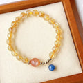 Gold rutilated quartz sunstone crystal bracelet with diamond-cut beads on wrist