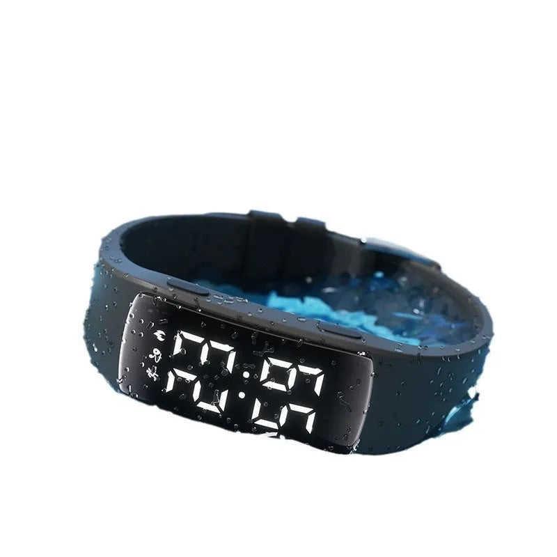 Black electronic digital watch with LED display and silicone strap on a wrist.