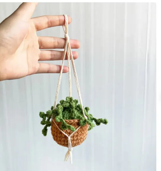 Green and white knitted wool car plant ornament hanging from a rope