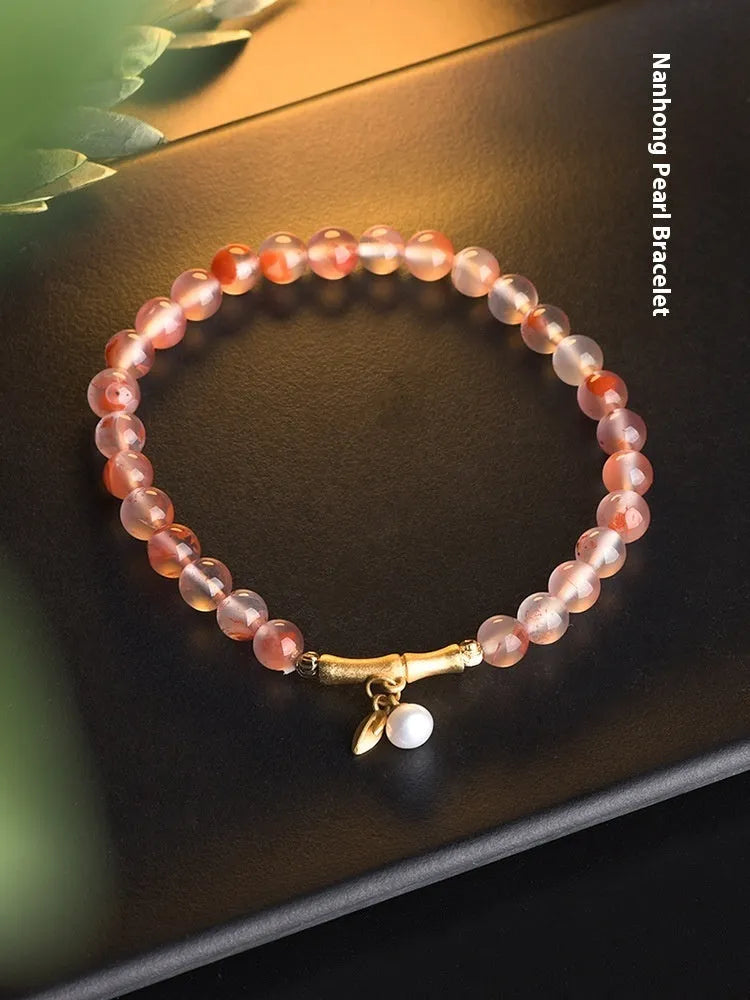 Polished Nanhong Agate flower bracelet with bamboo joint design on wrist.