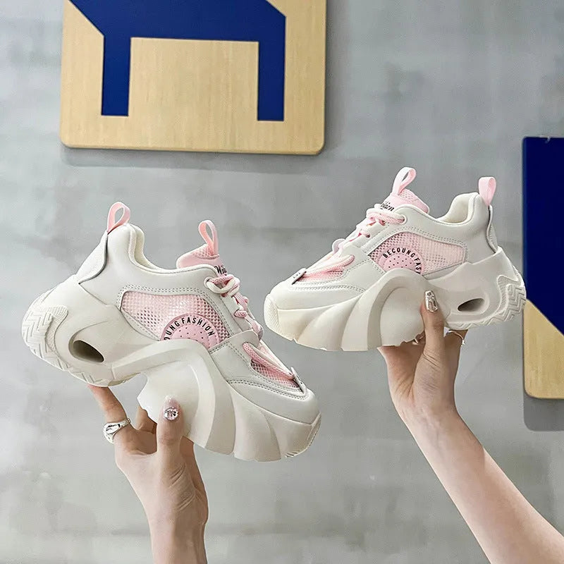Women's pink casual sneakers with a thick sole, cross-strap detail, and lace-up closure on a white background.