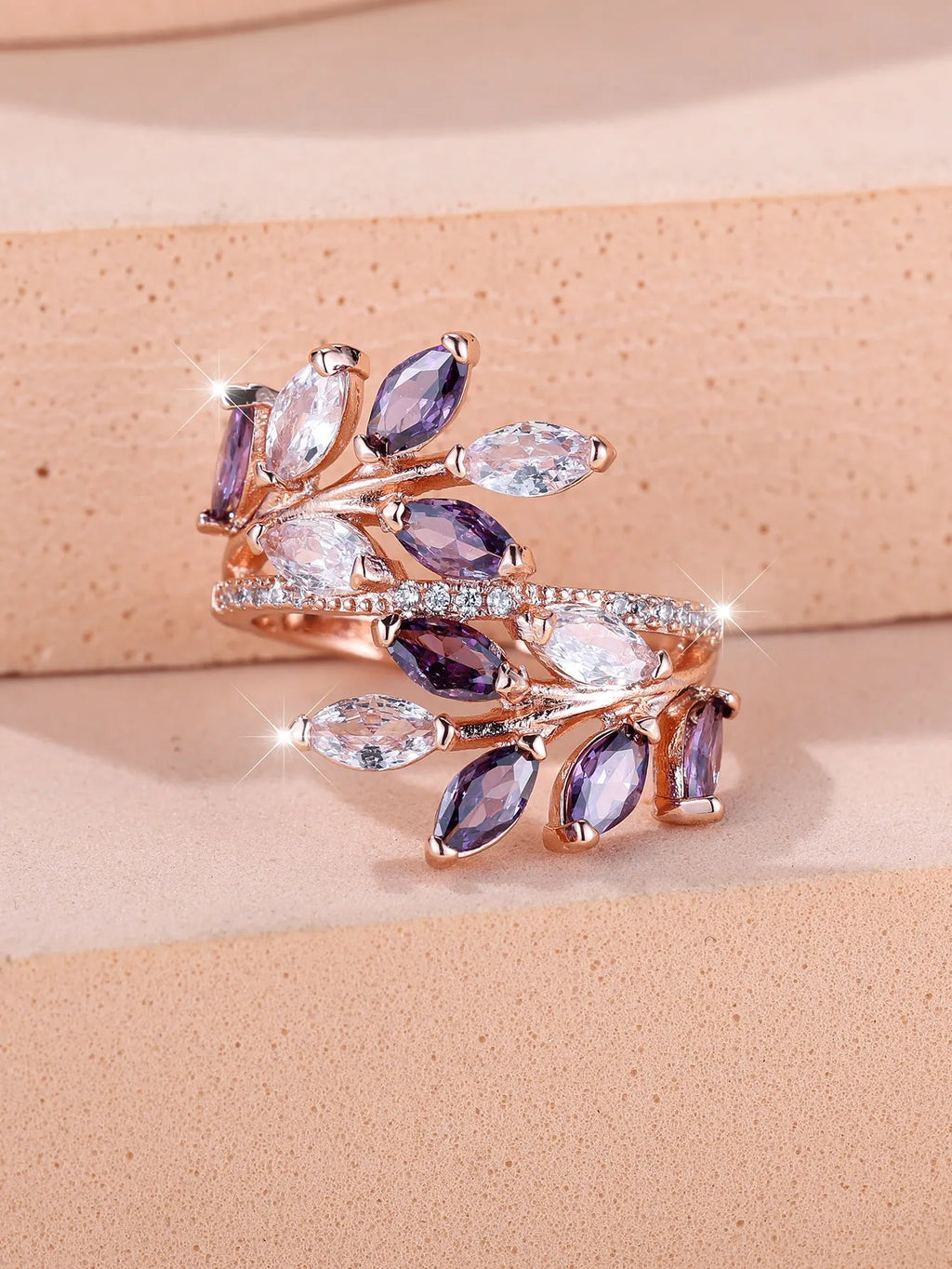 Adjustable copper leaf-shaped ring with sparkling zircon stones in rose gold and platinum finishes.