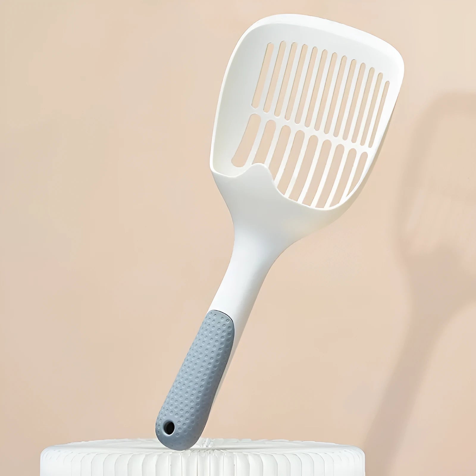 White plastic cat litter scoop with an attached storage base on a white background.