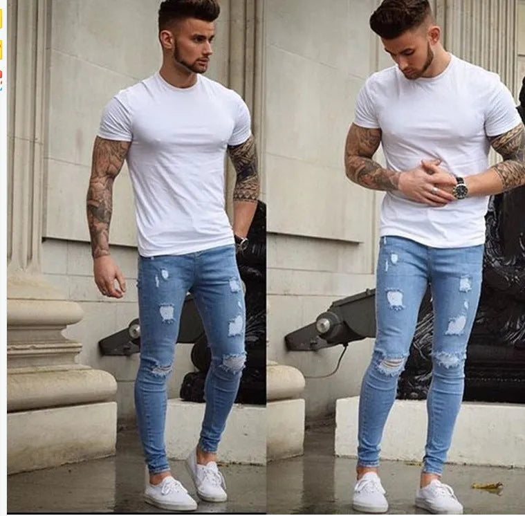 Frayed slim-fit jeans in blue, showing distressed hem and slim leg shape, on a model standing casually