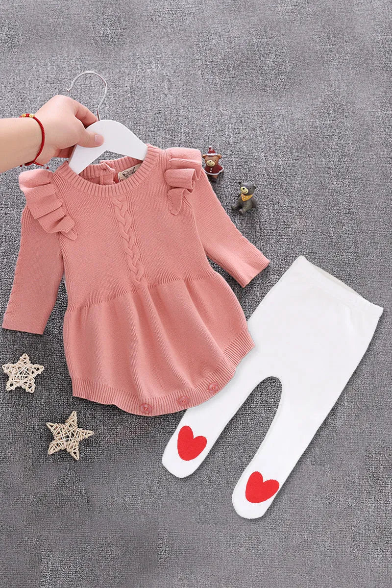Baby girl wearing a soft pink cotton princess-style romper with a hedging placket.