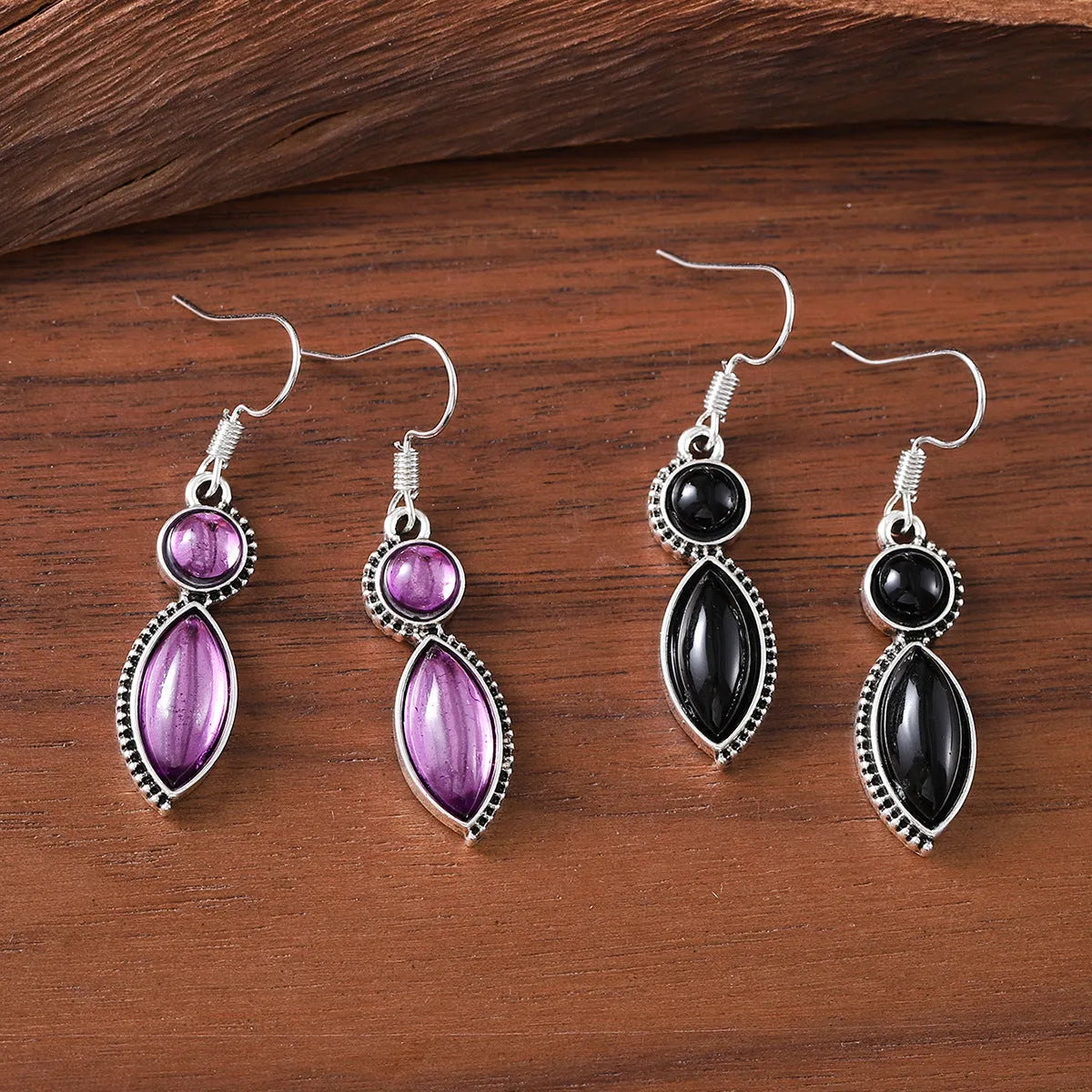 Vintage silver-tone geometric drop earrings with round purple and black stones on a grey background.