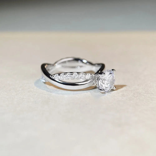 Sterling silver ring with a 1 karat moissanite stone, geometric cross design, and twisted band.