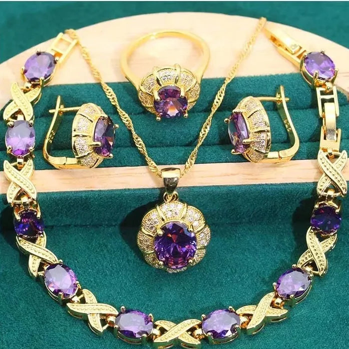 An 18k gold plated jewellery set with blue cubic zirconia stones, showing necklace, earrings, ring, and bracelet.