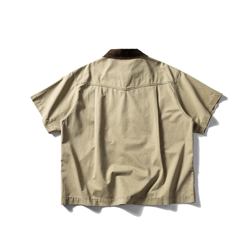 Washed grey cotton overalls shirt with short sleeves and a loose cardigan style on a hanger.