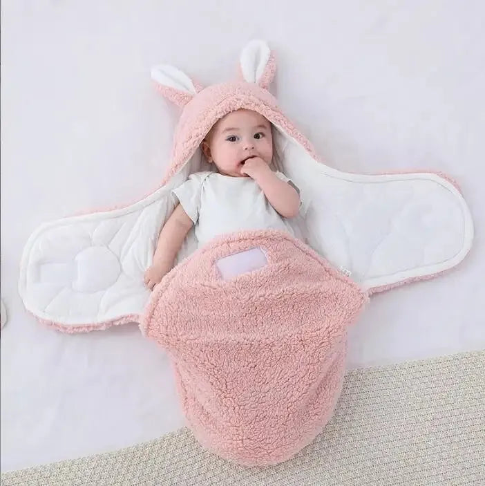 Baby wearing a grey adjustable fleece swaddle sleep sack with velcro wings