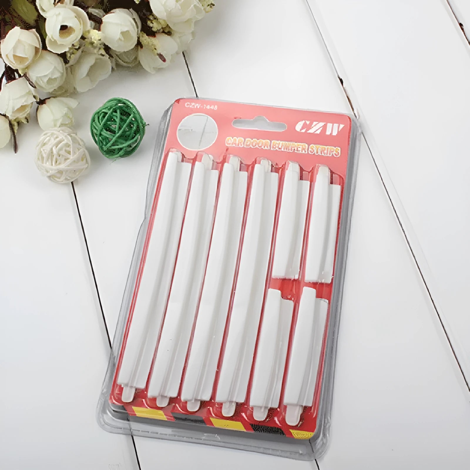 White plastic car door edge protection strip with adhesive backing, shown in packaging.