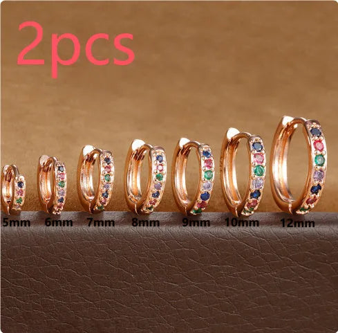 Gold, rose gold, and silver circle-shaped perforated stud earrings on a plain background.