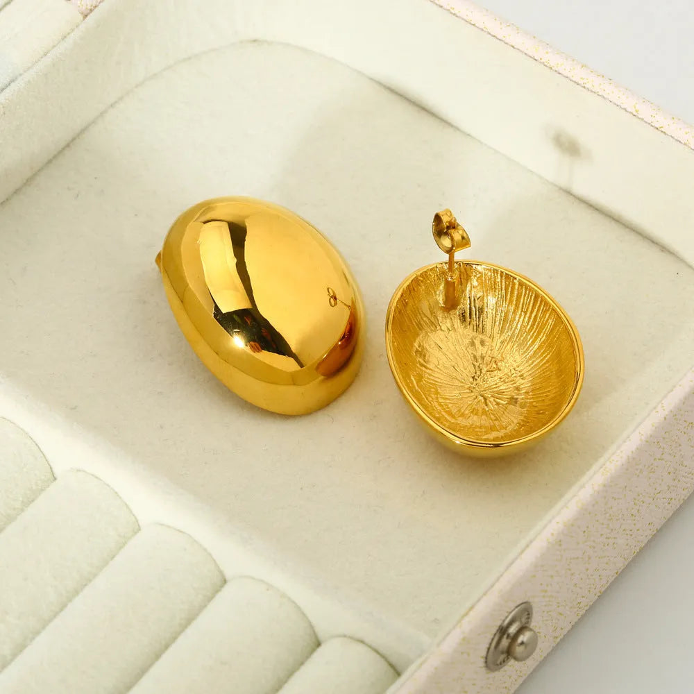Geometric gold-coloured ear studs with glazed surface and line design details