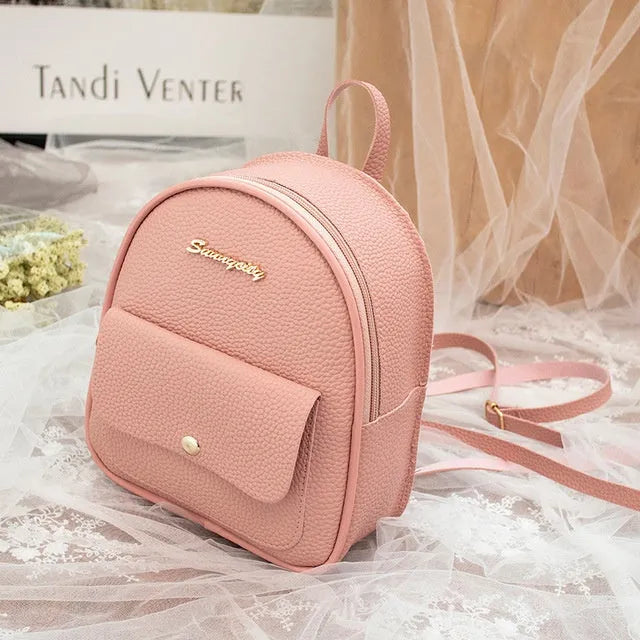 Compact black PU leather women's shoulder backpack worn crossbody, showing zipper closure and simple design.