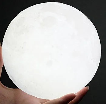 3D printed white moon lamp with detailed lunar surface texture on a wooden holder.
