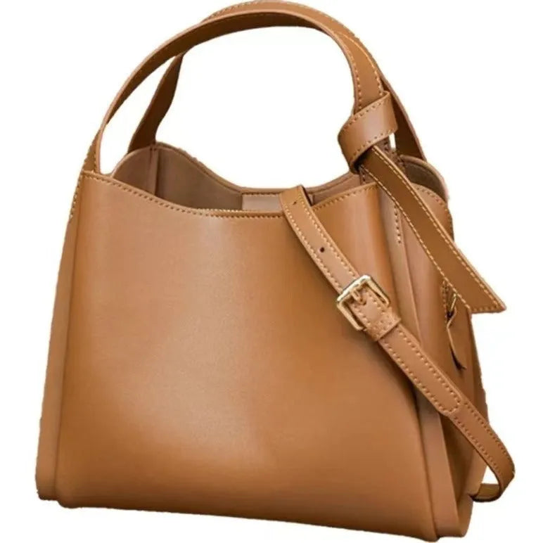 Brown cowhide leather women's bucket crossbody bag with visible stitching and a crossbody strap.