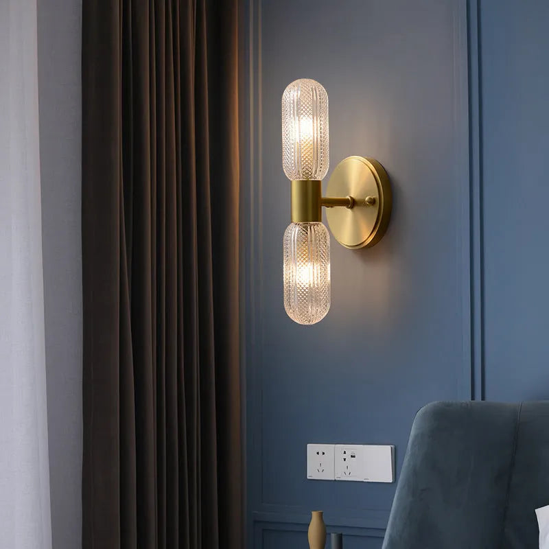 Modern double head wall lamp with a copper finish mounted on a light grey wall.