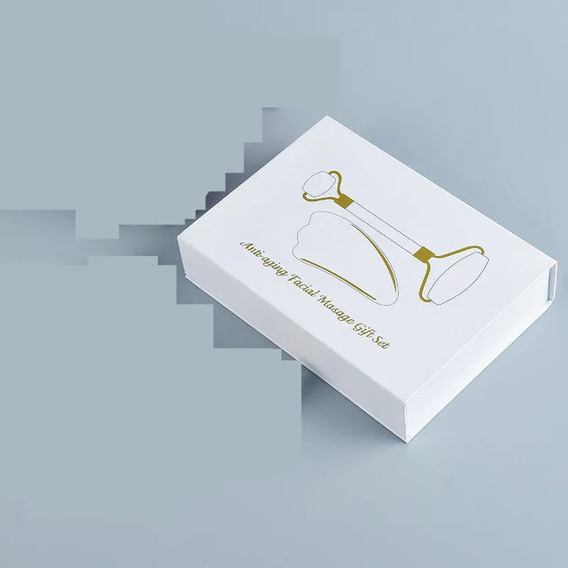 White jade double-headed roller and matching scraping board set on a flat surface.