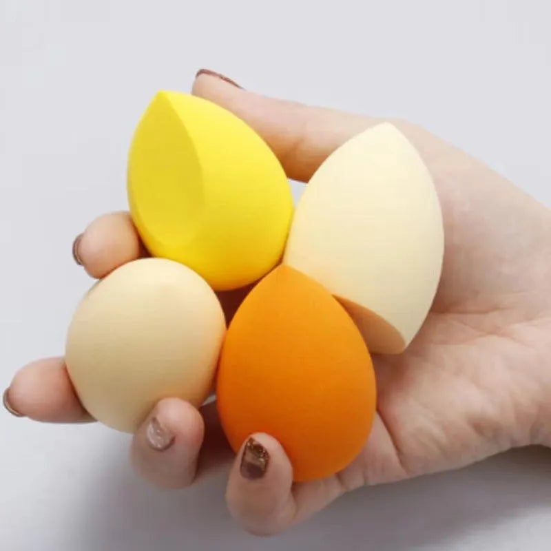 Seven different shaped makeup sponge puffs in various colours including pink, blue and burgundy