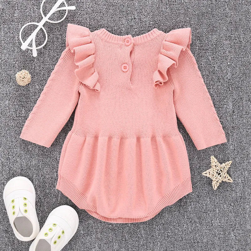Baby girl wearing a soft pink cotton princess-style romper with a hedging placket.