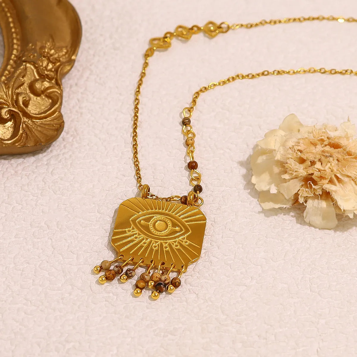 Retro gold titanium steel chain necklace with square natural stone pendant and evil eye motif on white background