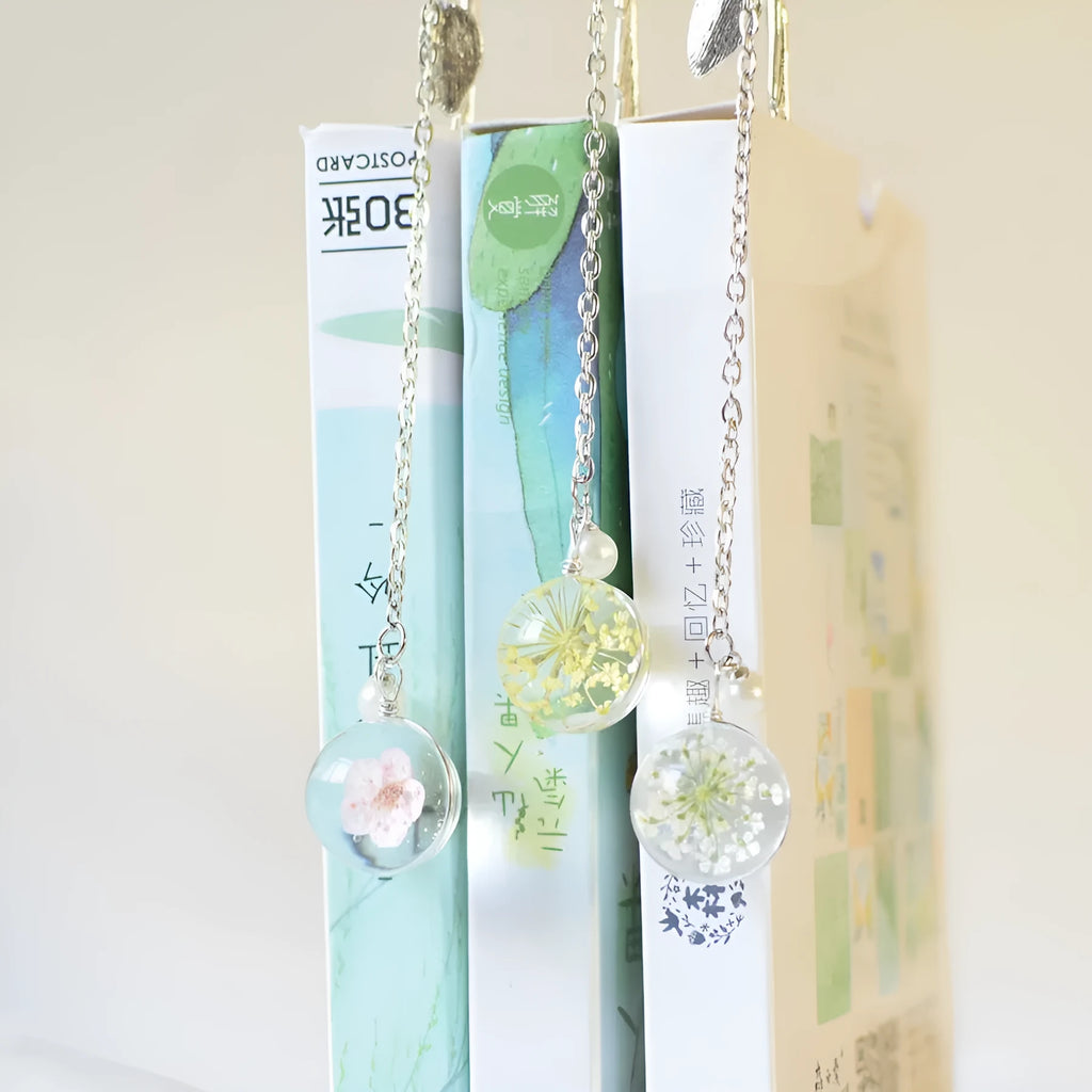 Close-up of a metal bookmark with a dried dandelion flower sealed inside, showing its 12cm length and slim profile.