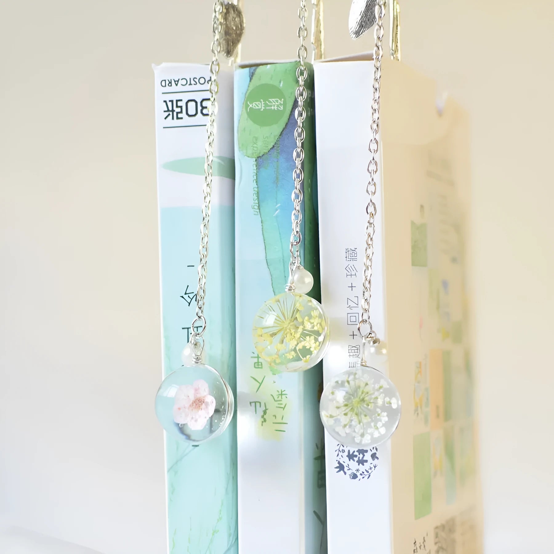 Close-up of a metal bookmark with a dried dandelion flower sealed inside, showing its 12cm length and slim profile.