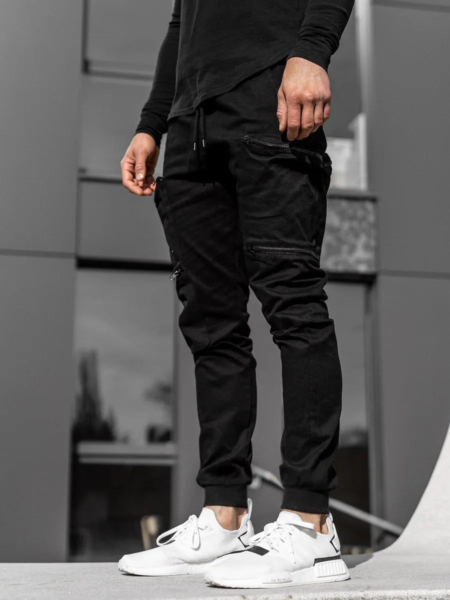 Men's tight fit multi-pocket cotton trousers in black, shown with multiple front pockets and tethered details on waistband.
