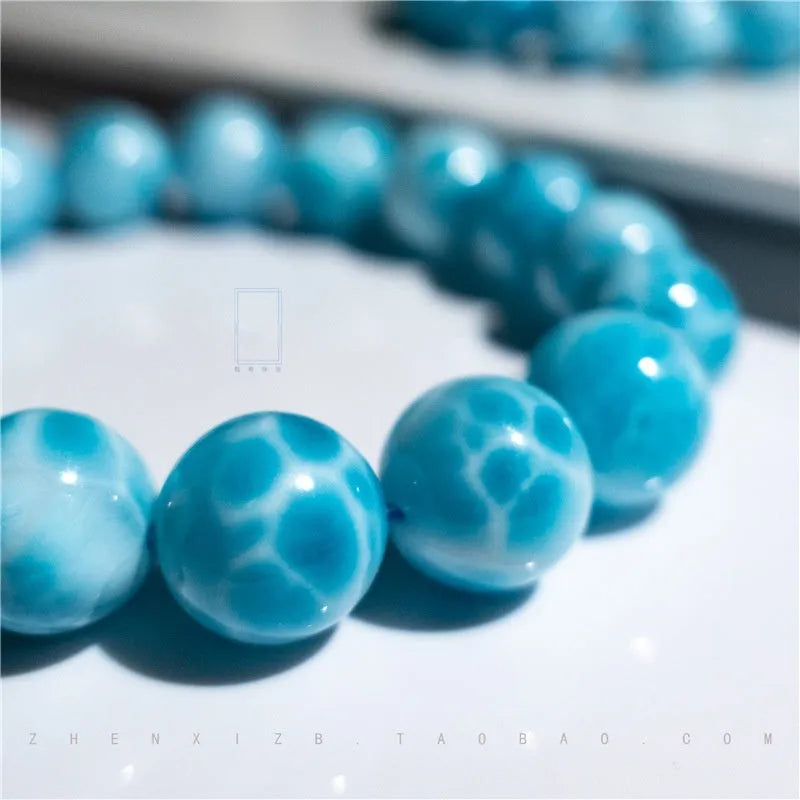 Blue bodhi bracelet with a sea-pattern natural crystal stone and small pearl accents on a wrist.
