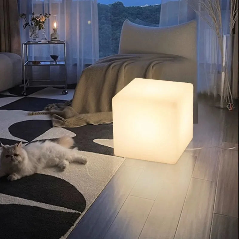 A white square cube LED stool light sitting on a patio, illustrating its modern design and outdoor use.