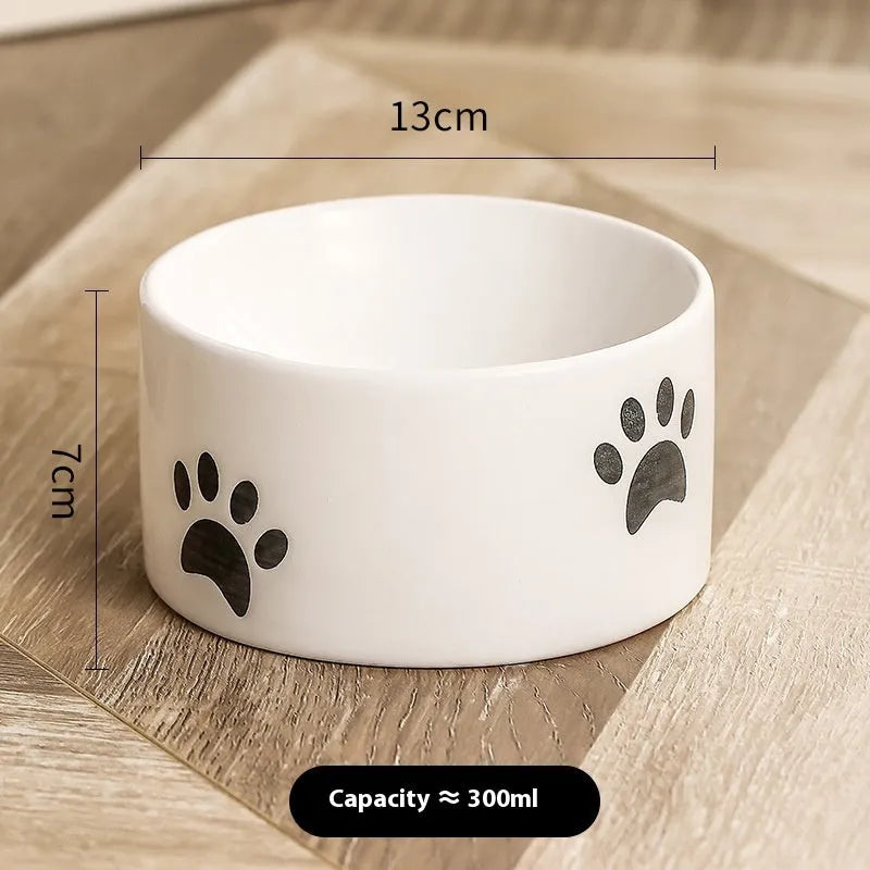 Ceramic cat food bowl with high foot base in a cat's paw print design
