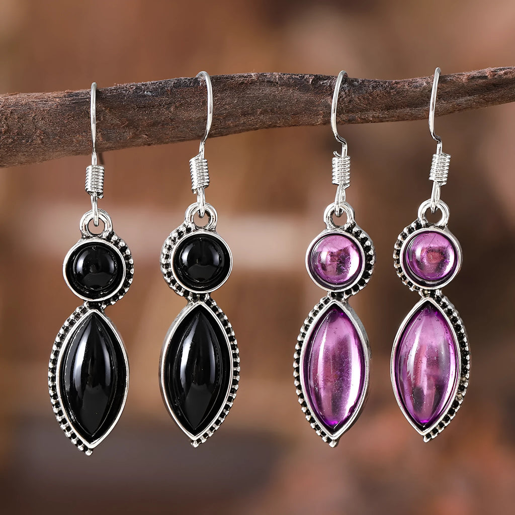 Vintage silver-tone geometric drop earrings with round purple and black stones on a grey background.