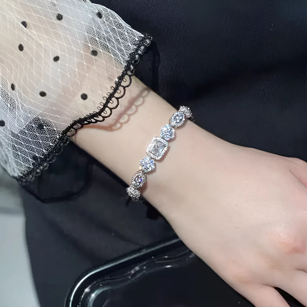 Close-up of a women's geometric silver bracelet with sparkling inlaid zircon stones and a lobster clasp.