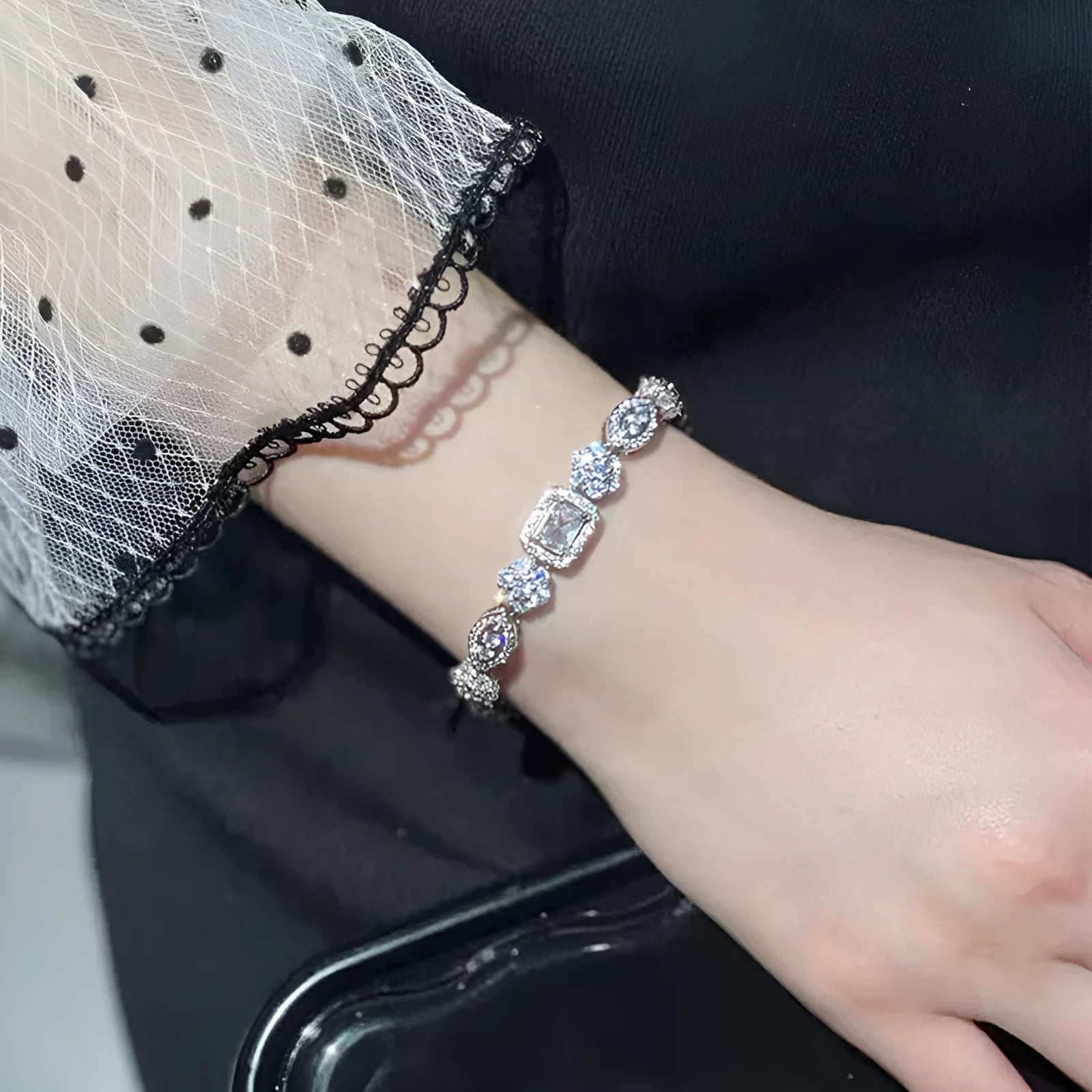 Close-up of a women's geometric silver bracelet with sparkling inlaid zircon stones and a lobster clasp.
