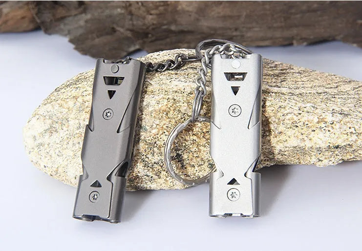 Compact metal keychain whistle with black lanyard on a keyring for outdoor emergency use