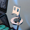 Aluminium alloy rotating mobile phone bracket in silver on a desk, showing three-axis joint and metal texture finish