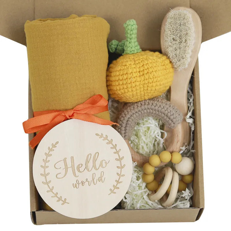 Baby teething toy gift set showing gauze blanket, wooden bell, gum teether, tire brush, and milestone on white background