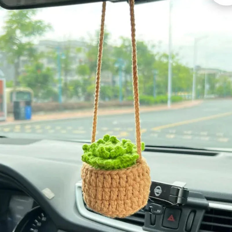 Green and white knitted wool car plant ornament hanging from a rope