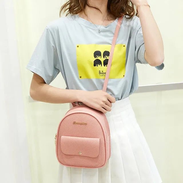 Compact black PU leather women's shoulder backpack worn crossbody, showing zipper closure and simple design.