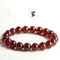 Natural orange red garnet crystal bracelet with ruyi design on a wrist.