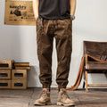 Man wearing khaki coloured cotton overalls with tapered legs and elasticated ankle bands.