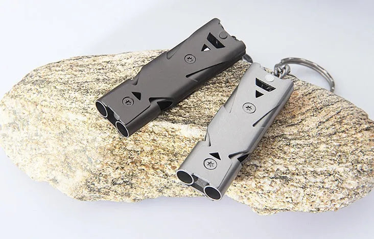 Compact metal keychain whistle with black lanyard on a keyring for outdoor emergency use