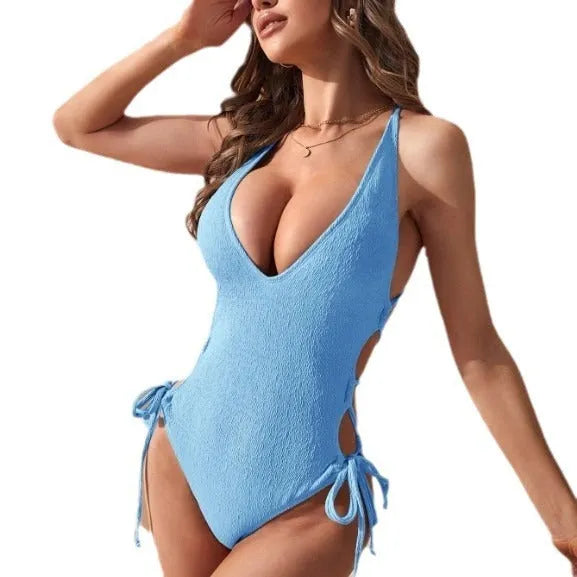 Women's black hollow backless one-piece swimsuit with central adjustable tether strap on back.