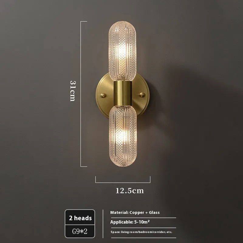 Modern double head wall lamp with a copper finish mounted on a light grey wall.