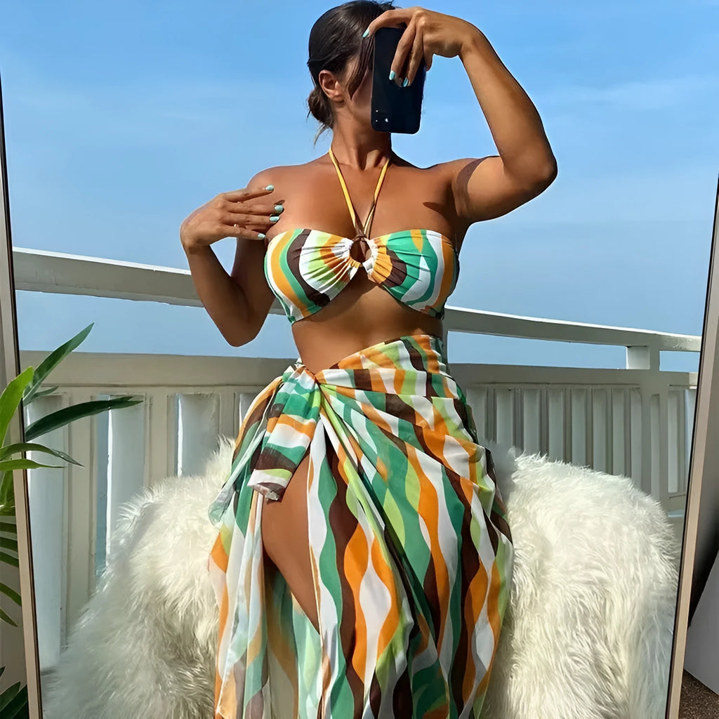 Yellow green printed women's bikini set with top, briefs, and matching beach skirt laid flat.