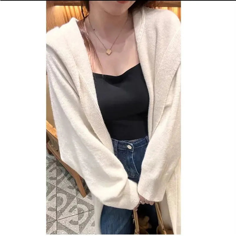 Long beige hooded knitted cardigan on a woman, showcasing its below-the-knee length and loose fit.