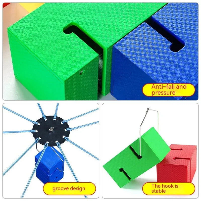 Outdoor team building game set showing coloured ABS plastic tower blocks, pull ropes, and a central hook frame on grass.