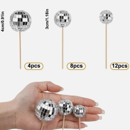 Glass disco ball cake decoration on a wooden stick in various sizes on a cake.